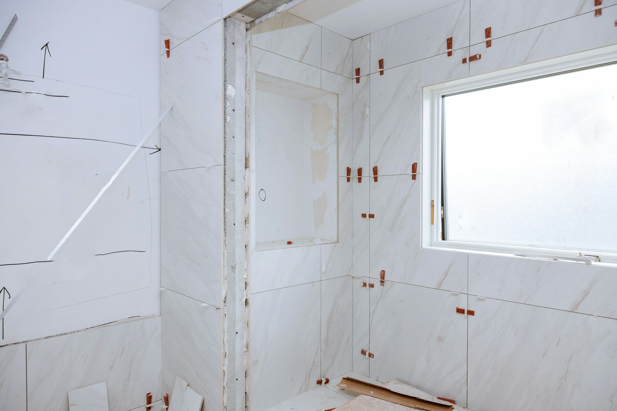 Work laying tile before applying tiles on bathroom tile.